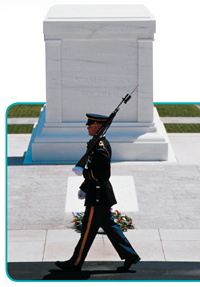 A uniformed soldier marches in front of a memorial.