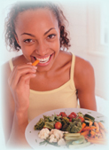 A woman eating vegetables from a dish with varieties of vegetables.