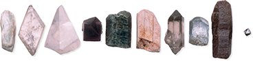 Several types of rocks and minerals of various shapes, sizes, and colors, lined up in a row.