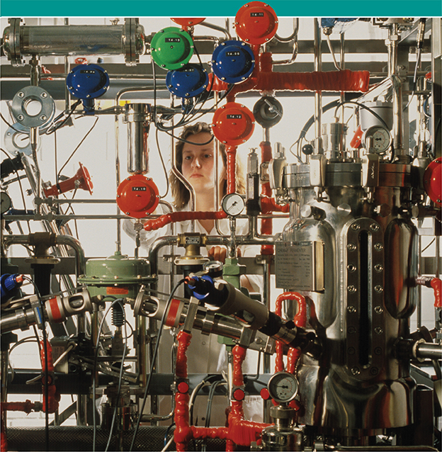 A scientist works behind large industrial machinery in a lab.