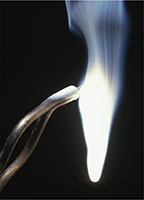 A magnesium ribbon held by small tongs burns to produce a dazzling white flame.