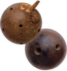 Two wooden spheres, one with small holes and one peg at the top. The second sphere has larger holes with no pegs. 