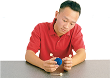 A male student works on making a model of a molecule out of foam balls.