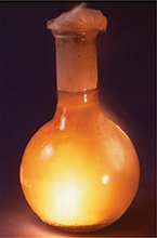 A glass vial producing a gas out of the top and glowing from the bottom.