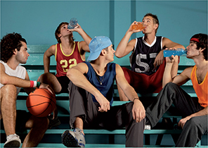 Male athletes drink beverages from bottles after a game. 