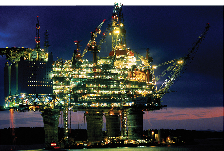 A large offshore oil platform, its different levels lighted up at night.