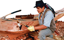 A man carving wood with axes and other sharp tools.