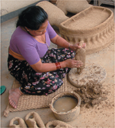 A woman puts layers of clay on top of a mold.