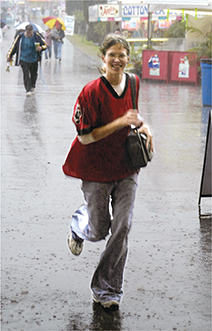 A young woman runs through the street in the rain.