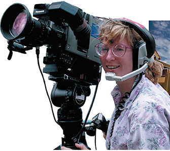 A woman operates a large video camera.