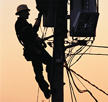 Silhouette of a person fixing the electrical box on an electric pole.