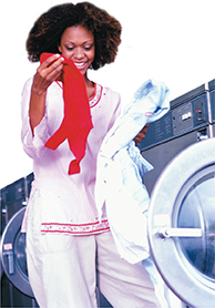 A woman removes laundry from a dryer.  