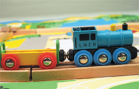 Two wooden toy train cars held together by magnetic force.