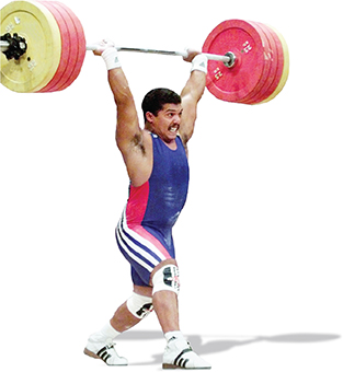A weight lifter lifts a barbell.