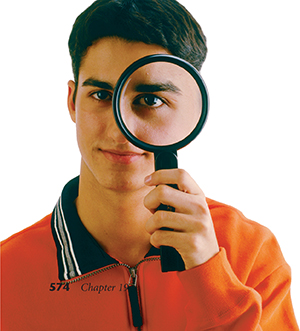 A boy looks through a magnifying glass. The eye that he uses to see is magnified.