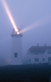Beams of light shine from a lighthouse tower.