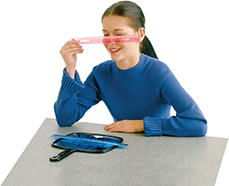 A female student at a desk looking at a ruler.  She is performing the experiment for this lab.