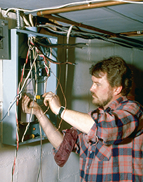 An electrician installing wiring in the main box of a house.