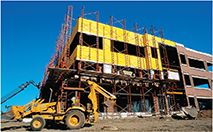 A bulldozer outside a building still under construction.