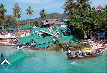 A village or town that was destroyed by the tsunami in 2004.  Homes are destroyed, and there is a rescue boat full of people in the water.