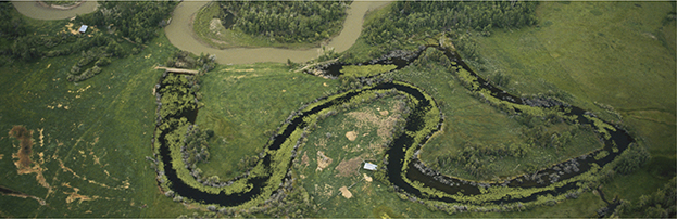 An aerial view of a winding meander and an oxbow lake, both created by water erosion.