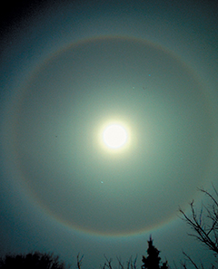 A moon in the night sky that looks like a halo has formed around it.