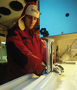 A scientist analyzing an ice core, a long cylinder of ice taken from a glacier.  He is inside a lab.