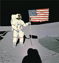 An astronaut on the Moon, posing for a photo holding onto a rod containing the US flag floating. Beneath the rod is a shadow of the astronaut taking the picture.