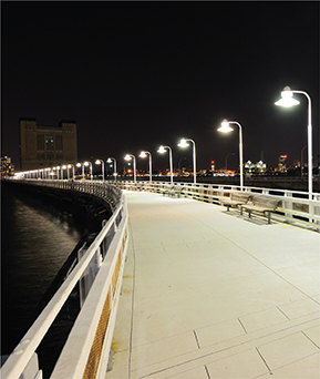 Street lights along a boardwalk which all have the same brightness even though the ones closer seem brighter.