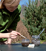 A female scientist using a litmus strip to test a substance in a jar.