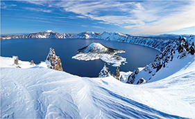 Photo of Crater Lake that is icy and covered in snow.