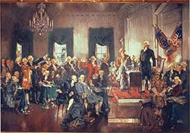 A painting of George Washington leading Congress. He is standing on a platform behind a desk, while some Congressmen are sitting and others are standing.