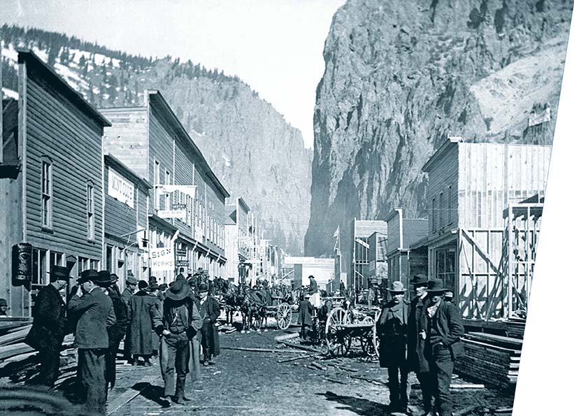 Many people, horses, and wagons gathered on a mountain town's main street