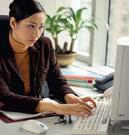An Asian woman sitting at a desk in front of a computer