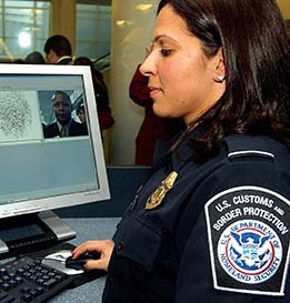 A photo of a traveler being screened by fingerprint and photo by a U.S. Customs and Border Protection worker.