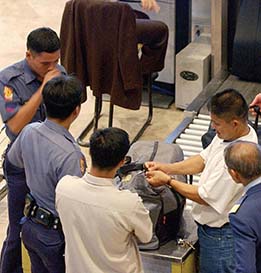 Airport security personnel examine a passenger's luggage.