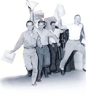 A group of happy men running, waving papers overhead.