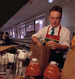 A man is bagging groceries in a grocery store. 