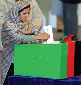 An Afghan woman casting a vote in a ballot box. 