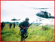 American soldiers in Vietnam during war and some helicopters flying above them.