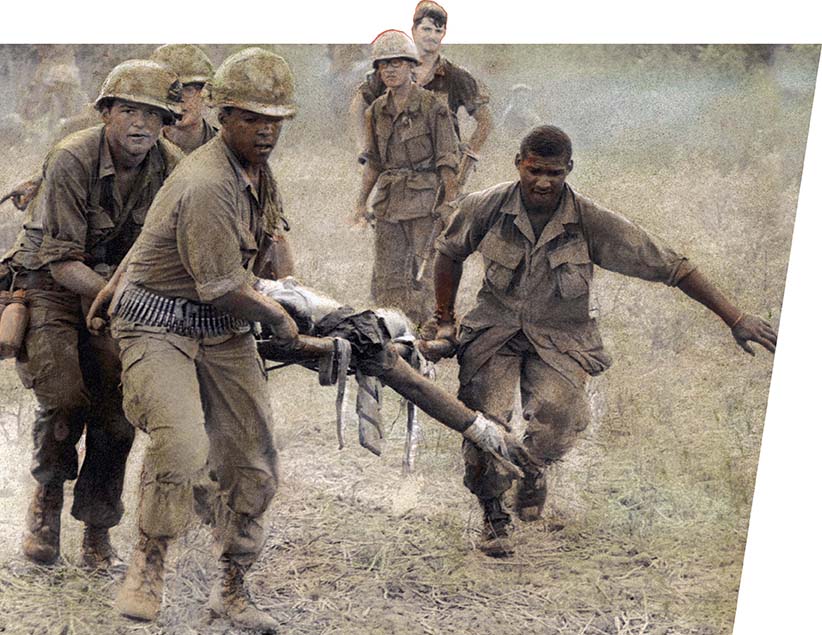 Soldiers carry a wounded soldier from the battlefield on a stretcher.