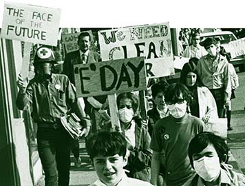 A photo in black and white of people holding up signs that reflect the awareness of the environmental movement.
