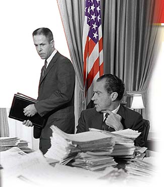 President Nixon, sitting at his desk in the oval office with many stacks of paper. His aide, H.R. Haldeman stands behind him.
