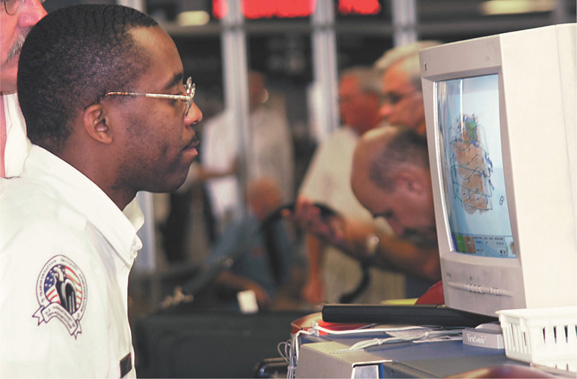 A TSA worker at a checkpoint looks at a computer screen.