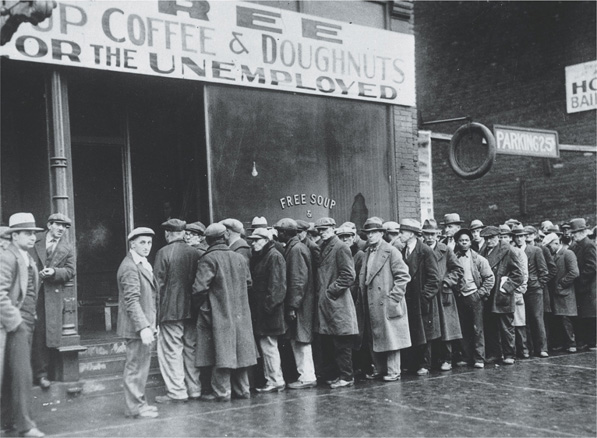People line up outside a building during the Great Depression. A sign advertises free coffee and doughnuts for the unemployed.